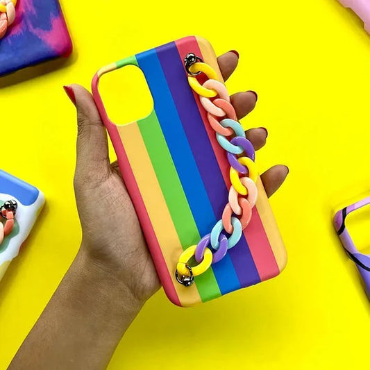 Hand holding rainbow striped phone case with colorful chain charm against yellow background