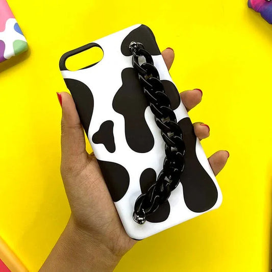 Black and white cow print phone case with black chain handle held in hand on yellow background
